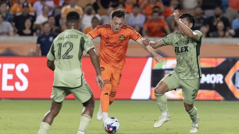 Jun 10, 2023; Houston, Texas, USA; Houston Dynamo FC forward Corey Baird (11) splits the defense of Los Angeles FC defender Diego Palacios (12) and defender Denil Maldonado (2) before scoring in the second half at Shell Energy Stadium. Mandatory Credit: Thomas Shea-USA TODAY Sports