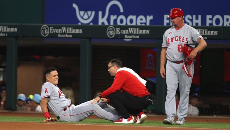 Jun 15, 2023; Arlington, Texas, USA; Los Angeles Angels third baseman Gio Urshela (10) is looked at by the trainer after injuring his knee in the first inning against the Texas Rangers at Globe Life Field. Mandatory Credit: Tim Heitman-USA TODAY Sports