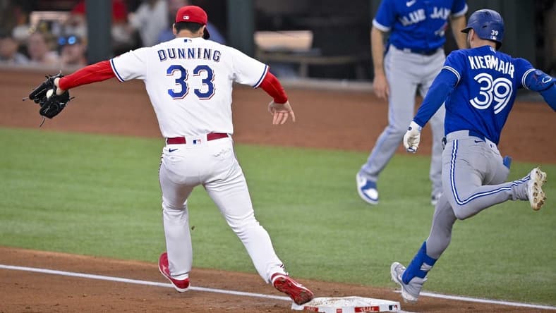 Jun 17, 2023; Arlington, Texas, USA; Texas Rangers starting pitcher Dane Dunning (33) puts out Toronto Blue Jays center fielder Kevin Kiermaier (39) at first base during the third inning at Globe Life Field. Mandatory Credit: Jerome Miron-USA TODAY Sports