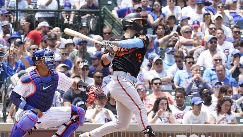 Jun 18, 2023; Chicago, Illinois, USA; Baltimore Orioles second baseman Adam Frazier (12) hits an RBI single against the Chicago Cubs during the sixth inning at Wrigley Field. Mandatory Credit: David Banks-USA TODAY Sports