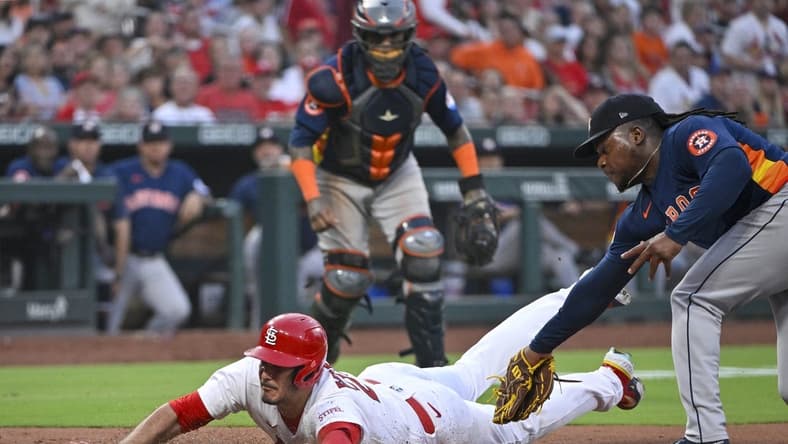 Jun 27, 2023; St. Louis, Missouri, USA; St. Louis Cardinals third baseman Nolan Arenado (28) slides in at homeplate as Houston Astros starting pitcher Framber Valdez (59) attempts to apply the tag during the fifth inning at Busch Stadium. Arenado was called out on the play but the call was overturned after a successful challenge by the Cardinals. Mandatory Credit: Jeff Curry-USA TODAY Sports