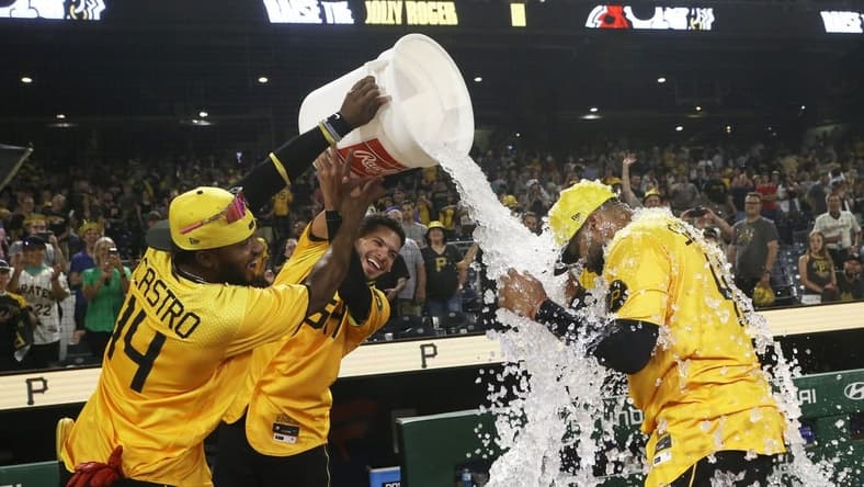 Jun 30, 2023; Pittsburgh, Pennsylvania, USA; Pittsburgh Pirates infielders Rodolfo Castro (14) and Tucupita Marcano (center) douse first baseman Carlos Santana after Santana hit a two-run walk-off home run to defeat the Milwaukee Brewers at PNC Park. Mandatory Credit: Charles LeClaire-USA TODAY Sports