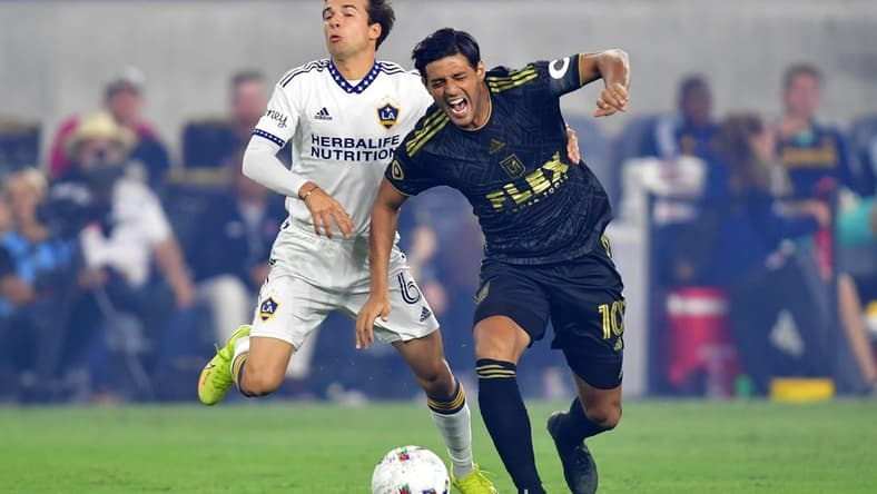 Oct 20, 2022; Los Angeles, California, US; Los Angeles Galaxy midfielder Riqui Puig Marti (6) collides with Los Angeles FC forward Carlos Vela (10) during the first half of the MLS Cup Playoff semifinal at Banc Of California Stadium. Mandatory Credit: Gary A. Vasquez-USA TODAY Sports