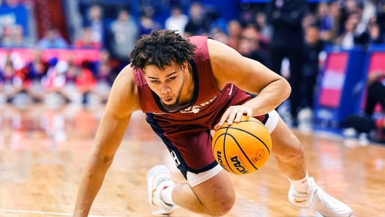 Dec 22, 2022; Lawrence, Kansas, USA; Harvard Crimson forward Chris Ledlum (4) slips while dribbling the ball during the first half against the Kansas Jayhawks at Allen Fieldhouse. Mandatory Credit: Jay Biggerstaff-USA TODAY Sports