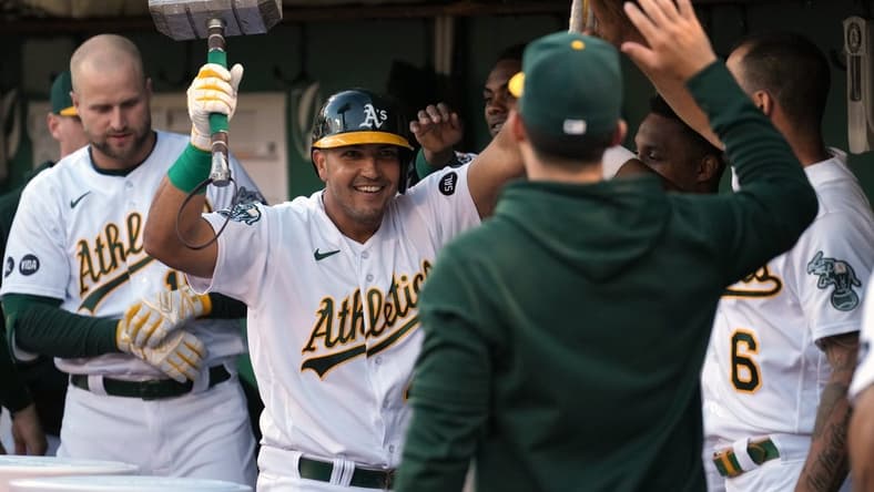 Jun 30, 2023; Oakland, California, USA; Oakland Athletics first baseman Carlos Perez (center) celebrates in the dugout while carrying a replica hammer after hitting a home run against the Chicago White Sox during the fifth inning at Oakland-Alameda County Coliseum. Mandatory Credit: Darren Yamashita-USA TODAY Sports