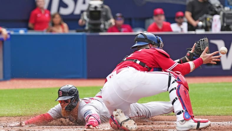 Jul 1, 2023; Toronto, Ontario, CAN; Boston Red Sox first baseman Justin Turner (2) slides into home plate scoring a run ahead of the tag from Toronto Blue Jays catcher Danny Jansen (9) during the fifth inning at Rogers Centre. Mandatory Credit: Nick Turchiaro-USA TODAY Sports