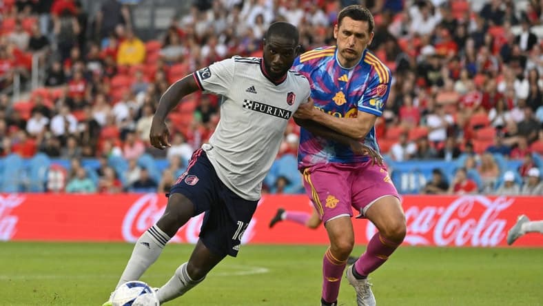 Jul 8, 2023; Toronto, Ontario, CAN;   St. Louis City forward Sam Adeniran (16) tries to dribble the ball past Toronto FC defender Shane O'Neill (27) in the first half at BMO Field. Mandatory Credit: Dan Hamilton-USA TODAY Sports