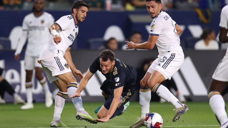 Jul 8, 2023; Carson, California, USA; Philadelphia Union midfielder Deniel Gazdag (10) dribbles against Los Angeles Galaxy midfielder Gaston Brugman (5) and midfielder Marco Delgado (8) during the first half at Dignity Health Sports Park. Mandatory Credit: Jason Parkhurst-USA TODAY Sports