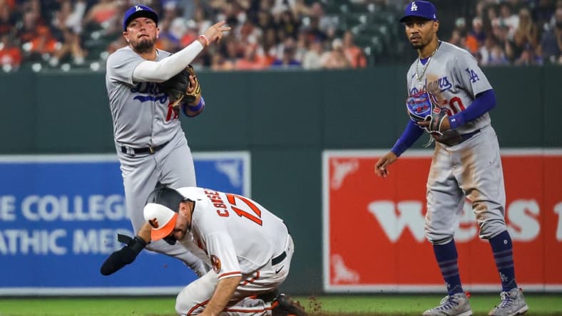 Jul 17, 2023; Baltimore, Maryland, USA; Los Angeles Dodgers shortstop Miguel Rojas (11) throws to first base over a sliding Baltimore Orioles outfielder Colton Cowser (17) as second baseman Mookie Betts (50) looks on in the ninth inning at Oriole Park at Camden Yards. Mandatory Credit: Tommy Gilligan-USA TODAY Sports