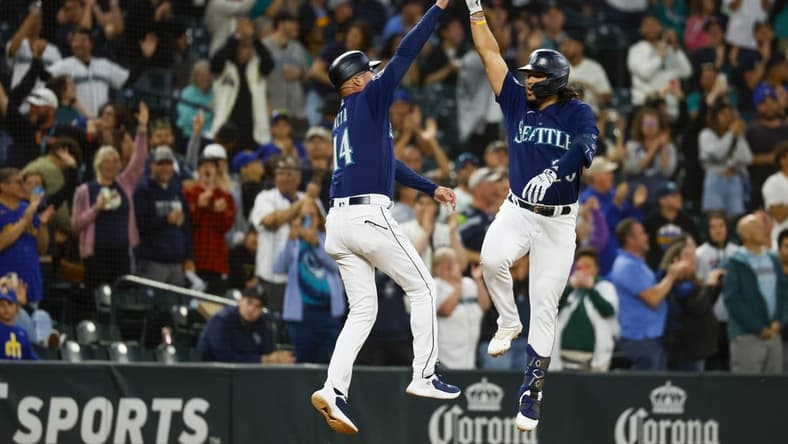 Jul 17, 2023; Seattle, Washington, USA; Seattle Mariners third baseman Eugenio Suarez (28) makes a jumping high-five with third base coach Manny Acta (14) while running the bases after hitting a two-run home run against the Minnesota Twins during the seventh inning at T-Mobile Park. Mandatory Credit: Joe Nicholson-USA TODAY Sports