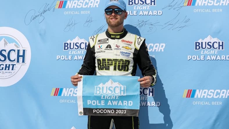Jul 22, 2023; Long Pond, Pennsylvania, USA; NASCAR Cup Series driver William Byron stands with the Busch Light Pole Award after winning the pole for the HighPoint.com 400 at Pocono Raceway. Mandatory Credit: Matthew O'Haren-USA TODAY Sports