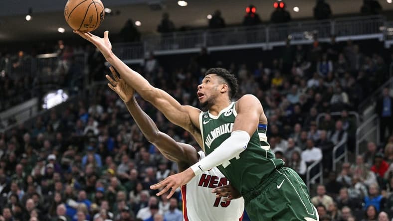Apr 26, 2023; Milwaukee, Wisconsin, USA; Milwaukee Bucks forward Giannis Antetokounmpo (34) lays up a shot against Miami Heat center Bam Adebayo (13) during game five of the 2023 NBA Playoffs at Fiserv Forum. Mandatory Credit: Michael McLoone-USA TODAY Sports