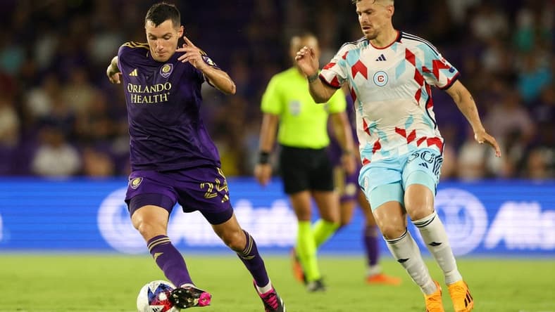 Jul 1, 2023; Orlando, Florida, USA;  Orlando City SC defender Kyle Smith (24) controls the ball from Chicago Fire FC midfielder Gaston Gimenez (30) in the second half at Exploria Stadium. Mandatory Credit: Nathan Ray Seebeck-USA TODAY Sports