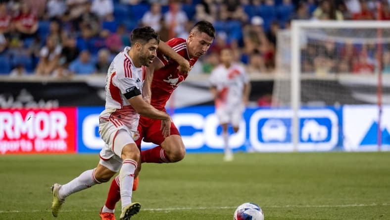 Jul 22, 2023; Harrison, NJ, USA; New England Revolution midfielder Carles Gil (10) fights for the ball against New York Red Bulls defender Sean Nealis (15) during the first half at Red Bull Arena. Mandatory Credit: Mark Smith-USA TODAY Sports