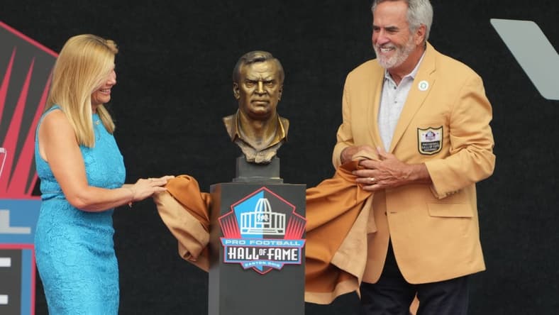 Aug 5, 2023; Canton, OH, USA; Dan Fouts and Mindy Coryell Lewis unveil the bust of San Diego Chargers and St. Louis Cardinals former coach Don Coryell (deceased) during the 2023 Pro Football Hall of Fame Enshrinement at Tom Benson Hall of Fame Stadium. Mandatory Credit: Kirby Lee-USA TODAY Sports