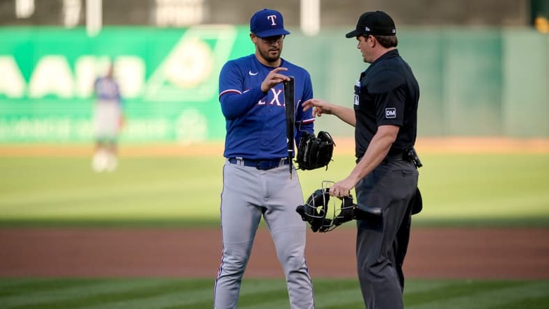 Aug 7, 2023; Oakland, California, USA; Texas Rangers starting pitcher Dane Dunning (33) hands a piece of a broken bat to home plate umpire Adam Beck (38) during the first inning at Oakland-Alameda County Coliseum. Mandatory Credit: Robert Edwards-USA TODAY Sports