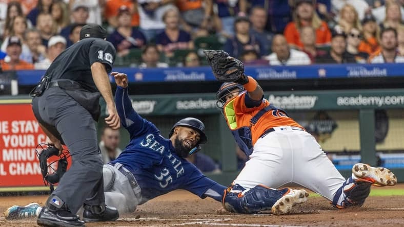 Aug 18, 2023; Houston, Texas, USA; Home plate umpire Alex MacKay calls Seattle Mariners right fielder Teoscar Hernandez (35) out at home as he is tagged by Houston Astros catcher Martin Maldonado (15)  in the fourth inning at Minute Maid Park. Mandatory Credit: Thomas Shea-USA TODAY Sports