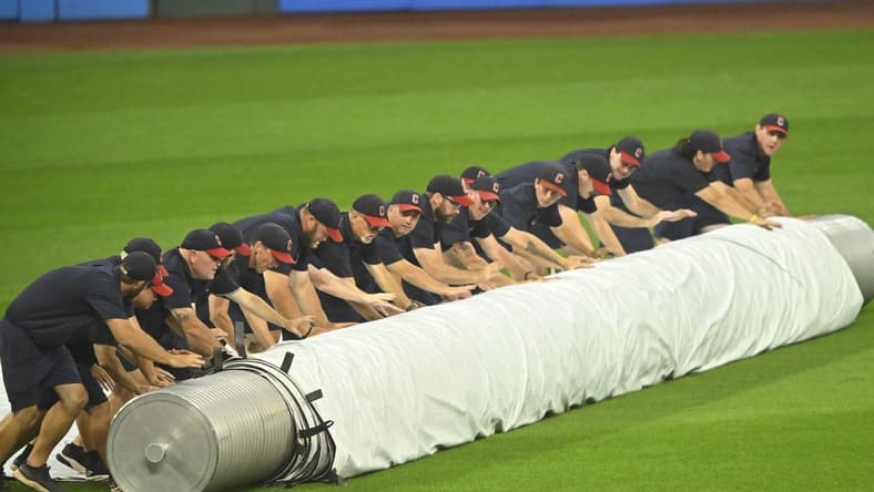 Aug 23, 2023; Cleveland, Ohio, USA; The Cleveland Guardians grounds crew unrolls the tarp on the field during a rain delay after the second inning against the Los Angeles Dodgers at Progressive Field. Mandatory Credit: David Richard-USA TODAY Sports