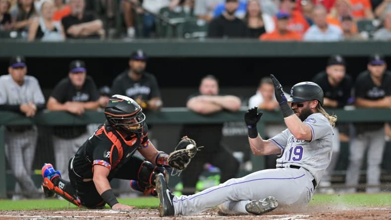 Aug 25, 2023; Baltimore, Maryland, USA; Colorado Rockies designated hitter Charlie Blackmon (19) slides past Baltimore Orioles catcher James McCann (27) to score during the second inning at Oriole Park at Camden Yards. Mandatory Credit: Tommy Gilligan-USA TODAY Sports