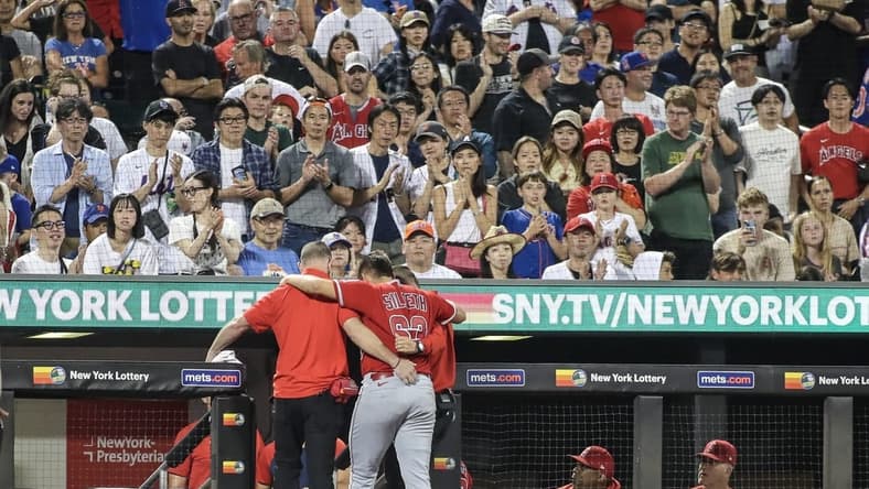 Aug 26, 2023; New York City, New York, USA;  Los Angeles Angels starting pitcher Chase Silseth (63) is helped back into the dugout after getting hit in the head by a throw in the fourth inning against the New York Mets at Citi Field. Mandatory Credit: Wendell Cruz-USA TODAY Sports
