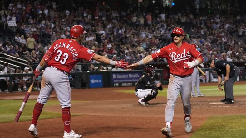 Aug 26, 2023; Phoenix, Arizona, USA; Cincinnati Reds center fielder TJ Friedl (29) slaps hands with Cincinnati Reds first baseman Christian Encarnacion-Strand (33) after scoring a run against the Arizona Diamondbacks during the 11th inning at Chase Field. Mandatory Credit: Joe Camporeale-USA TODAY Sports