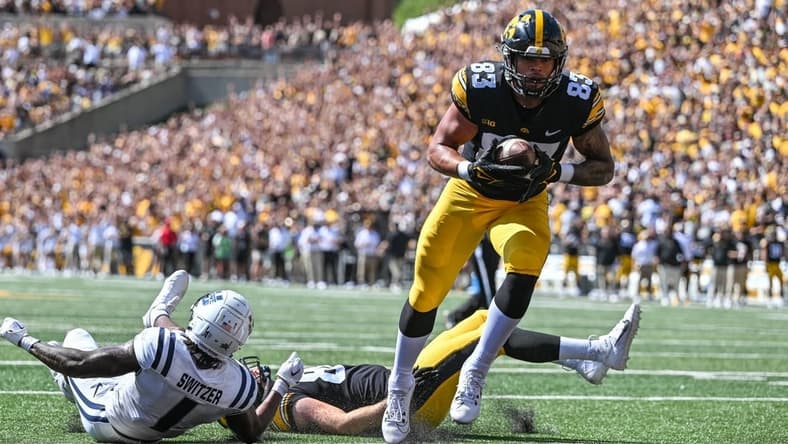 Sep 2, 2023; Iowa City, Iowa, USA; Iowa Hawkeyes tight end Erick All (83) scores on a touchdown pass as Utah State Aggies safety Anthony Switzer (1) and Iowa tight end Steven Stilianos (86) lay on the turf during the first quarter at Kinnick Stadium. Mandatory Credit: Jeffrey Becker-USA TODAY Sports