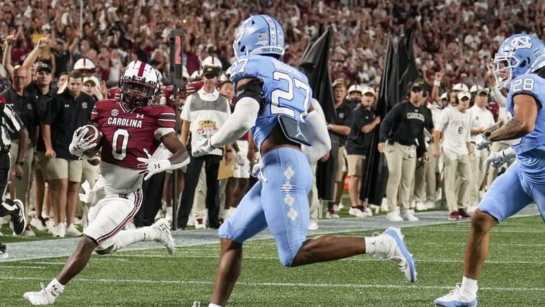 Sep 2, 2023; Charlotte, North Carolina, USA; South Carolina Gamecocks running back Juju McDowell (0) runs towards the end zone chased by North Carolina Tar Heels defensive back Giovanni Biggers (27) during the second quarter at Bank of America Stadium. Mandatory Credit: Jim Dedmon-USA TODAY Sports