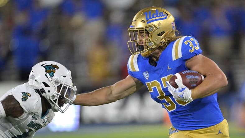 Sep 2, 2023; Pasadena, California, USA;  UCLA Bruins running back Carson Steele (33) pushes off Coastal Carolina Chanticleers safety Tobias Fletcher (4) for a first down in the first half at Rose Bowl. Mandatory Credit: Jayne Kamin-Oncea-USA TODAY Sports