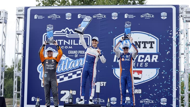 Sep 3, 2023; Portland, Oregon, USA; NTT Indy Car driver Alex Palou (center) lifts his first place trophy with second place finisher Felix Rosenqvist (left) and third place finisher Scott Dixon (right) at Portland International Raceway. Mandatory Credit: Soobum Im-USA TODAY Sports