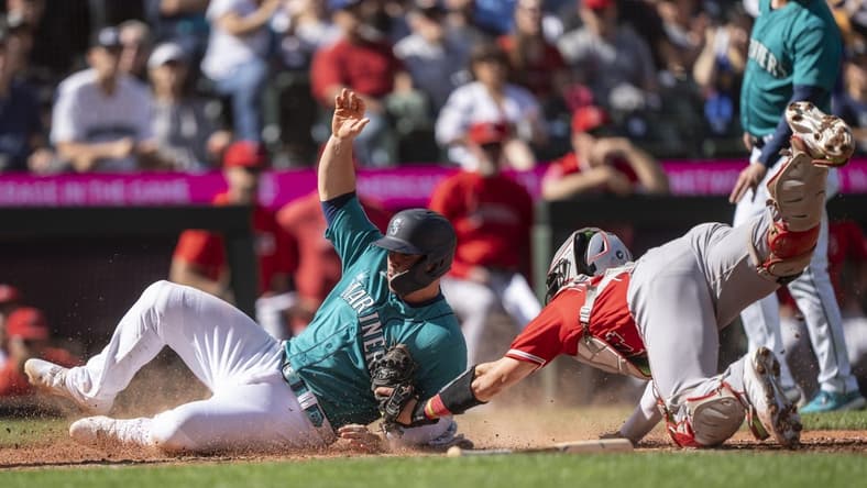 Sep 13, 2023; Seattle, Washington, USA; Seattle Mariners second baseman Ty France (23) slides safely into home plate to score a run against Los Angeles Angels catcher Logan O'Hoppe (14) during the fifth inning at T-Mobile Park. Mandatory Credit: Stephen Brashear-USA TODAY Sports