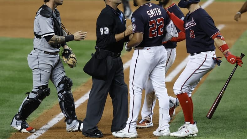 Sep 18, 2023; Washington, District of Columbia, USA; Washington Nationals first baseman Dominic Smith (22) is restrained from Chicago White Sox starting pitcher Mike Clevinger (not pictured) after hitting a home run by home plate umpire Will Little (93) as White Sox catcher Yasmani Grandal (24) steps in during the ninth inning at Nationals Park. Mandatory Credit: Geoff Burke-USA TODAY Sports