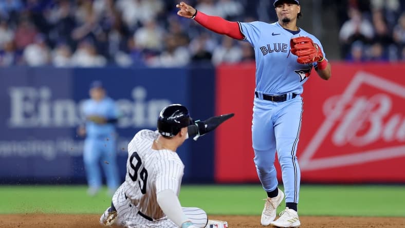 Sep 19, 2023; Bronx, New York, USA; Toronto Blue Jays second baseman Santiago Espinal (5) forces out New York Yankees right fielder Aaron Judge (99) at second and throws to first to complete a game ending double play on a ball hit by Yankees designated hitter Giancarlo Stanton (not pictured) during the ninth inning at Yankee Stadium. Mandatory Credit: Brad Penner-USA TODAY Sports