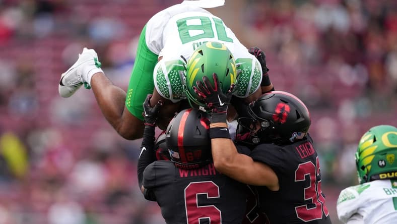 Sep 30, 2023; Stanford, California, USA; Oregon Ducks tight end Kenyon Sadiq (18) attempts to leap over Stanford Cardinal cornerback Collin Wright (6) and safety Mitch Leigber (32) during the second quarter at Stanford Stadium. Mandatory Credit: Darren Yamashita-USA TODAY Sports