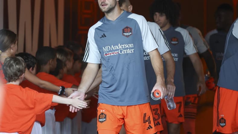 Aug 30, 2023; Houston, Texas, USA; Houston Dynamo FC defender Ethan Bartlow (4) and Dynamo FC players greet children in the tunnel before the match against the Columbus Crew SC at Shell Energy Stadium. Mandatory Credit: Troy Taormina-USA TODAY Sports
