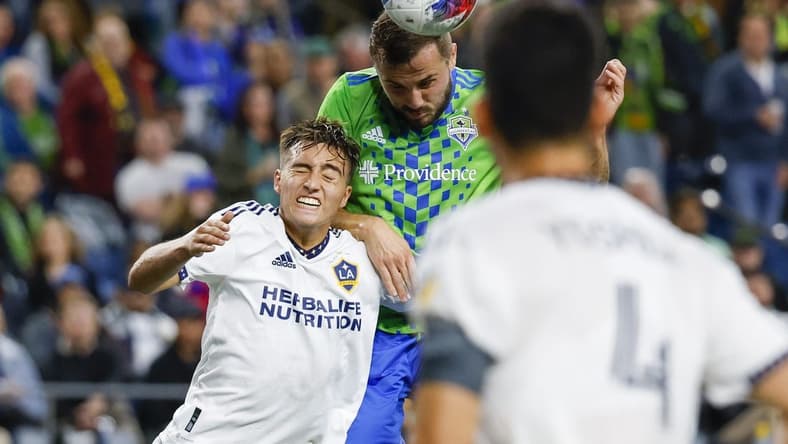 Oct 4, 2023; Seattle, Washington, USA; Seattle Sounders FC forward Jordan Morris (13, right) heads a cross against Los Angeles Galaxy defender Julian Aude (3) during the first half at Lumen Field. Mandatory Credit: Joe Nicholson-USA TODAY Sports