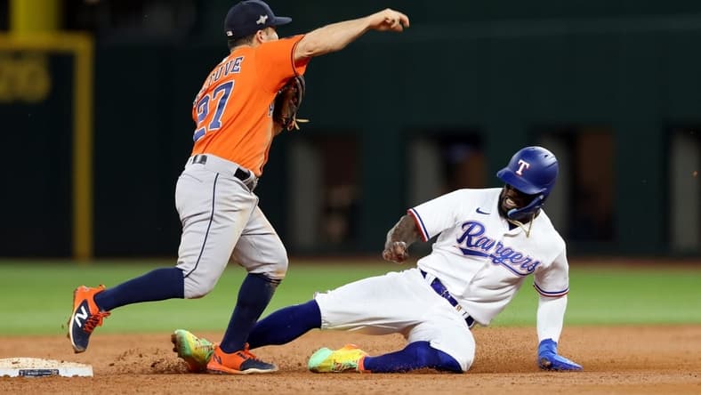 Oct 19, 2023; Arlington, Texas, USA; Houston Astros second baseman Jose Altuve (27) turns a double play against Texas Rangers right fielder Adolis Garcia (53) during the third inning in game four of the ALCS for the 2023 MLB playoffs at Globe Life Field. Mandatory Credit: Andrew Dieb-USA TODAY Sports