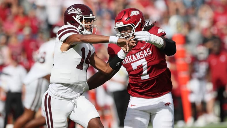 Oct 21, 2023; Fayetteville, Arkansas, USA; Mississippi State Bulldogs quarterback Mike Wright (14) throws a pass against Arkansas Razorbacks defensive lineman Trajan Jeffcoat (7) during the first quarter at Donald W. Reynolds Razorback Stadium. Mandatory Credit: Nelson Chenault-USA TODAY Sports