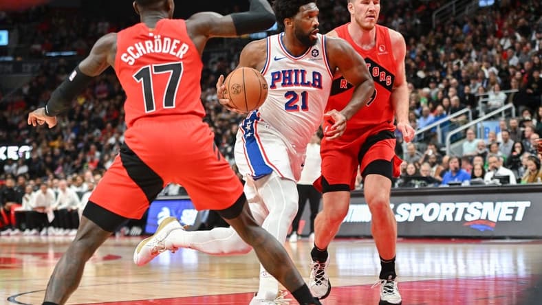 Oct 28, 2023; Toronto, Ontario, CAN; Philadelphia 76ers center Joel Embiid (21) drives to the basket between Toronto Raptors center Jakob Poeltl (19) and guard Dennis Schroder (17) in the first half at Scotiabank Arena. Mandatory Credit: Dan Hamilton-USA TODAY Sports
