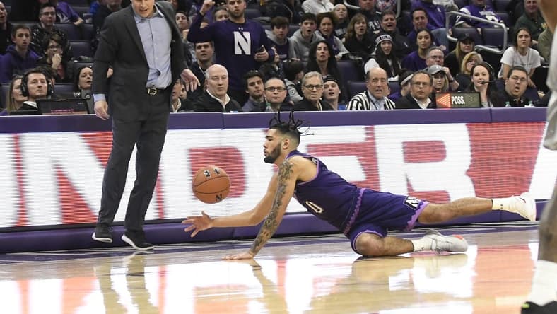 Mar 7, 2020; Evanston, Illinois, USA; Northwestern Wildcats guard Boo Buie (0) dives for the ball as Northwestern Wildcats head coach Chris Collins stands nearby during the second half at Welsh-Ryan Arena. Mandatory Credit: David Banks-USA TODAY Sports