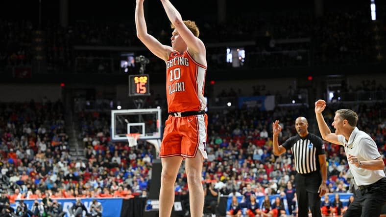 Mar 16, 2023; Des Moines, IA, USA; Illinois Fighting Illini guard Luke Goode (10) shoots the ball as Arkansas Razorbacks head coach Eric Musselman reacts during the first half at Wells Fargo Arena. Mandatory Credit: Jeffrey Becker-USA TODAY Sports