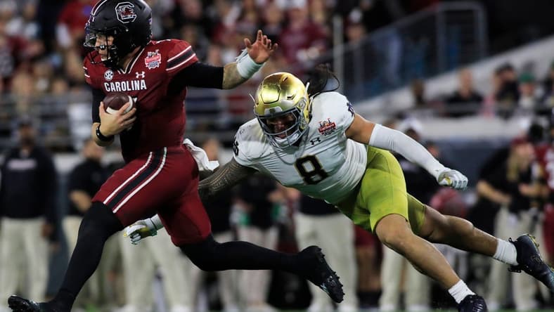 Notre Dame Fighting Irish linebacker Marist Liufau (8) tries to sack the South Carolina Quarterback Spencer Rattler (7). The University of Notre Dame Fighting Irish took on the University of South Carolina Gamecocks in the TaxSlayer Gator Bowl game in Jacksonville, Florida's TIAA Bank Field Friday, December 30, 2022. The first half ended with South Carolina holding a 24 to 17 lead.