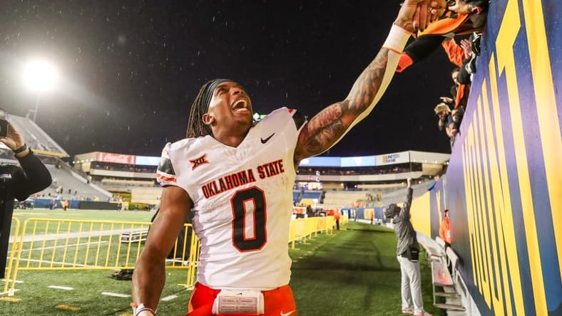 Oct 21, 2023; Morgantown, West Virginia, USA; Oklahoma State Cowboys running back Ollie Gordon II (0) celebrates with fans after defeating the West Virginia Mountaineers at Mountaineer Field at Milan Puskar Stadium. Mandatory Credit: Ben Queen-USA TODAY Sports