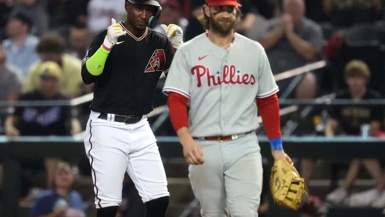 Arizona Diamondbacks shortstop Geraldo Perdomo (left) reacts after hitting a single during the seventh inning as Philadelphia Phillies first baseman Bryce Harper (right) looks on in game four of the NLCS of the 2023 MLB playoffs at Chase Field in Phoenix on Oct. 20, 2023.