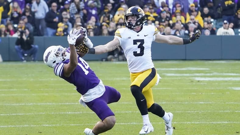 Nov 4, 2023; Chicago, Illinois, USA; Northwestern Wildcats wide receiver Cam Johnson (14) tries to catch a pass as Iowa Hawkeyes defensive back Cooper DeJean (3) defends during the first half at Wrigley Field. Mandatory Credit: David Banks-USA TODAY Sports