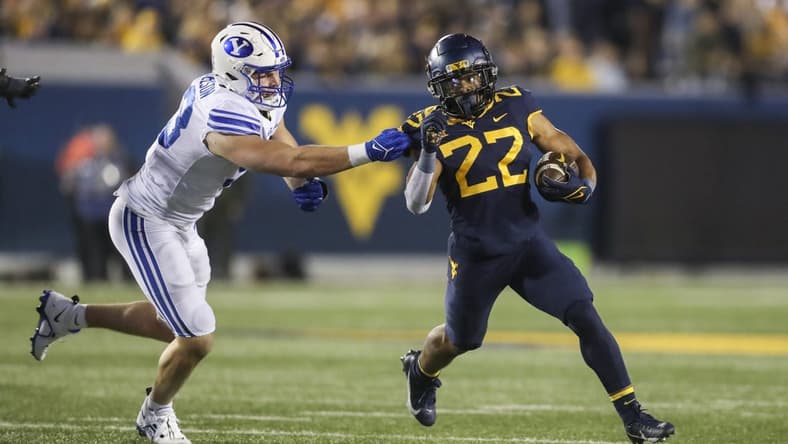 Nov 4, 2023; Morgantown, West Virginia, USA; West Virginia Mountaineers running back Jahiem White (22) runs the ball and avoids a tackle from Brigham Young Cougars defensive end Blake Mangelson (93) during the second quarter at Mountaineer Field at Milan Puskar Stadium. Mandatory Credit: Ben Queen-USA TODAY Sports