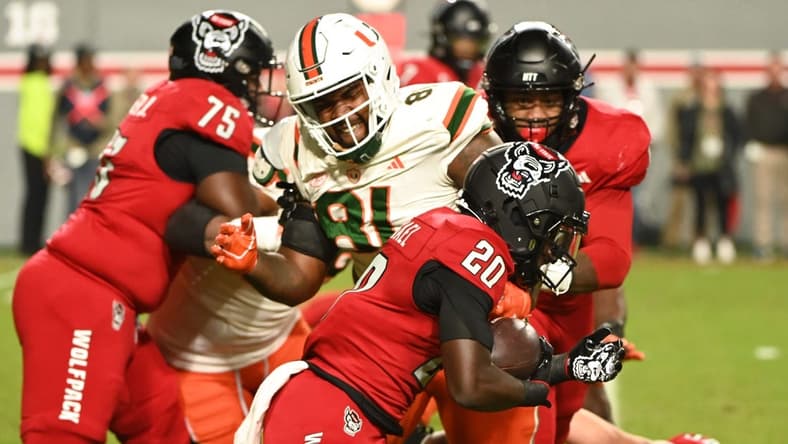Nov 4, 2023; Raleigh, North Carolina, USA; North Carolina State Wolfpack running back Kendrick Raphael (20) runs as Miami Hurricanes defensive lineman Jared Harrison-Hunte (81) defends during the first half at Carter-Finley Stadium. Mandatory Credit: Rob Kinnan-USA TODAY Sports