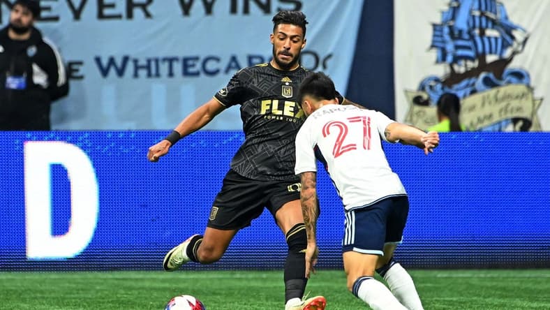 Nov 5, 2023; Vancouver, British Columbia, CAN; Los Angeles FC forward Denis Bouanga (99) kicks the ball against Vancouver Whitecaps midfielder Ryan Raposo (27) during the second half of game two in a round one match of the 2023 MLS Cup Playoffs at BC Place. Mandatory Credit: Simon Fearn-USA TODAY Sports