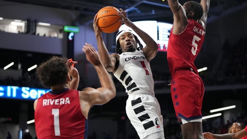 Cincinnati Bearcats guard Day Day Thomas (1) rises to the basket as Illinois-Chicago Flames guard Toby Okani (5) and Illinois-Chicago Flames guard Isaiah Rivera (1) defend in the first half of a men   s college basketball game between the Illinois-Chicago Flames and the Cincinnati Bearcats, Monday, Nov. 6, 2023, at Fifth Third Arena in Cincinnati.