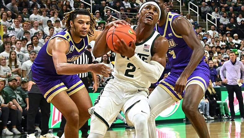 Nov 6, 2023; East Lansing, Michigan, USA; Michigan State Spartans guard Tyson Walker (2) drives through James Madison Dukes forward T.J. Bickerstaff (3) and guard Bryant Randleman (4) during the second half at Jack Breslin Student Events Center. Mandatory Credit: Dale Young-USA TODAY Sports