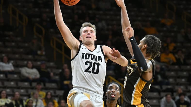 Oct 30, 2023; Iowa City, IA, USA; Iowa Hawkeyes forward Payton Sandfort (20) goes to the basket as Quincy University Hawks forward Jamil Wilson (23) and forward John Kelly III (4) defend during the first half at Carver Hawkeye Arena. Mandatory Credit: Jeffrey Becker-USA TODAY Sports